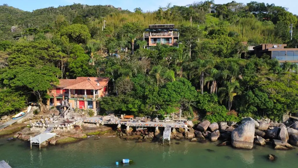 Vista aérea da pousada de frente para o mar, com o deck sobre as pedras