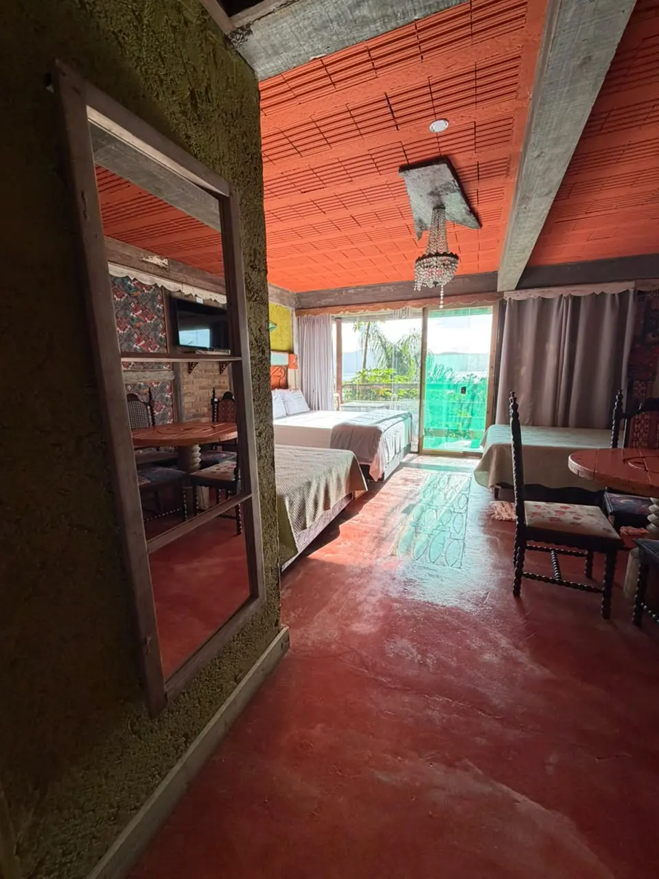 Suíte ampla com três camas, mesa e porta de vidro para a varanda